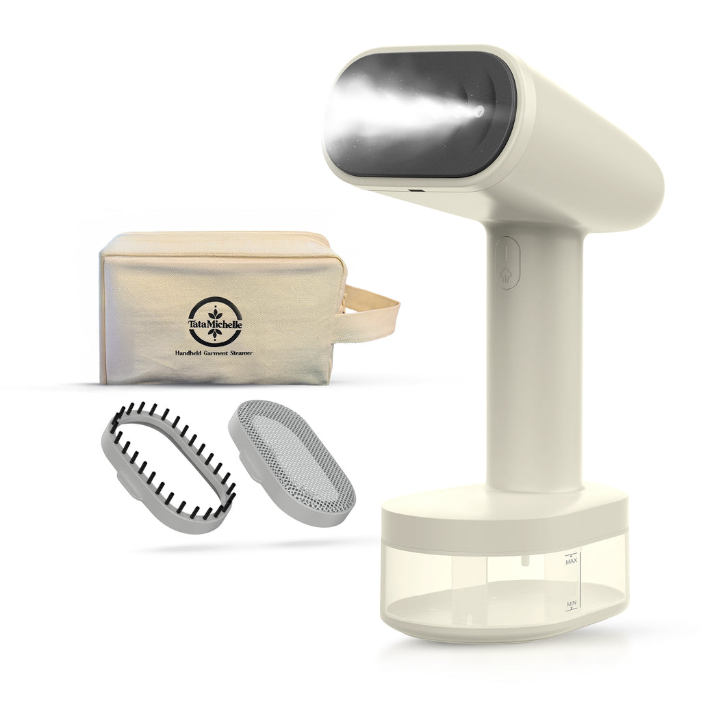 TataMichelle handheld garment steamer in cream white with included fabric brush, mesh attachment, and canvas travel storage bag